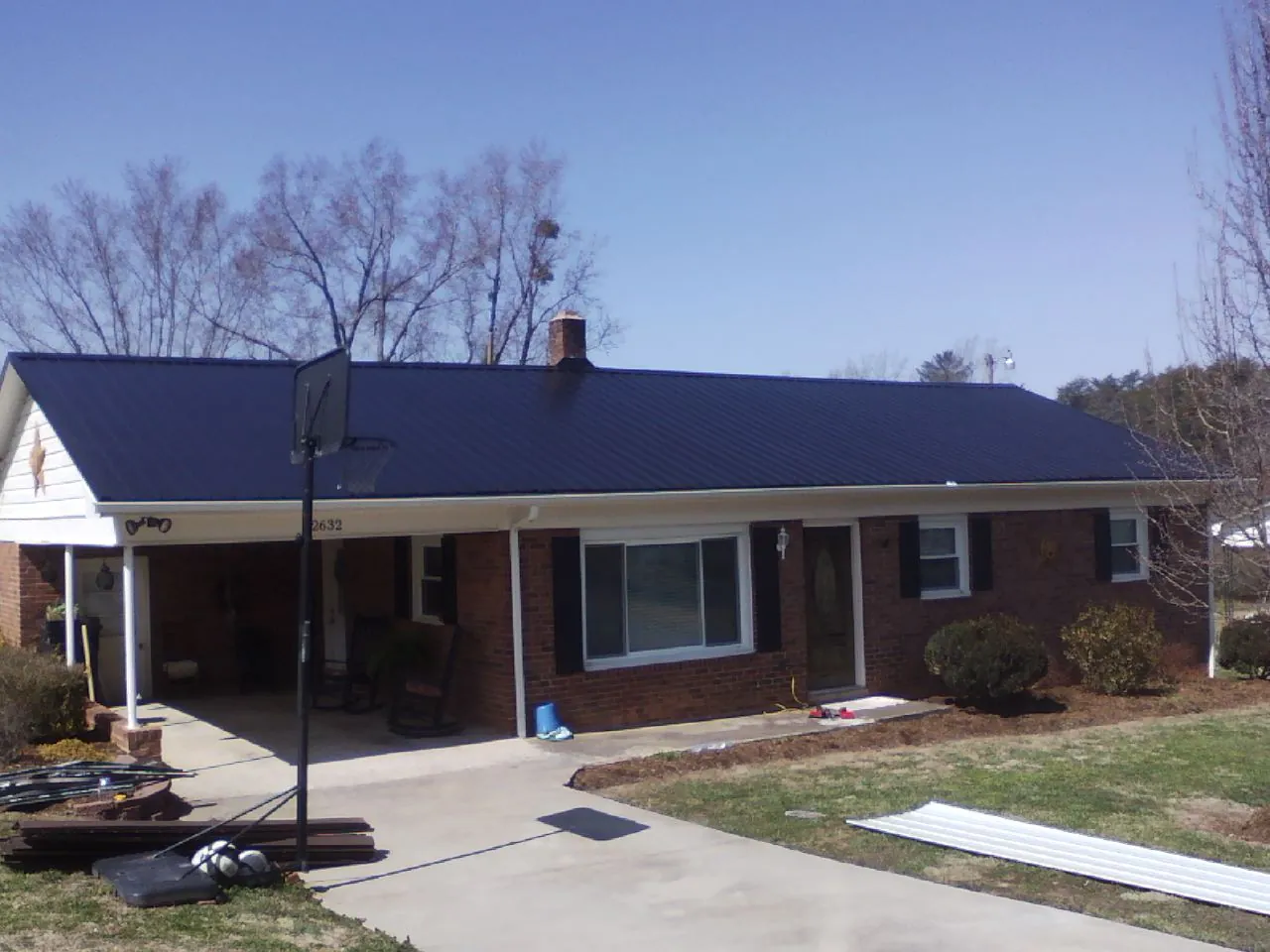 Finished dark blue metal roof on a brick ranch with a carport in Unionville